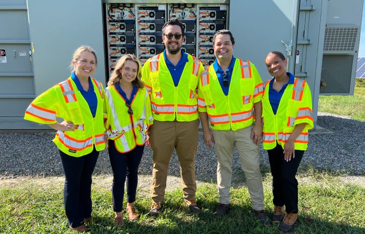 five people wearing high visibility vests on work site