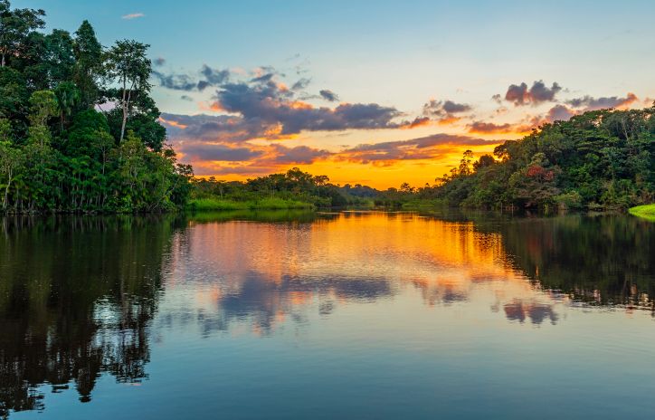 a lagoon surrounded by nature and trees as the sunsets